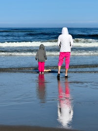 a woman and a child walking on the beach