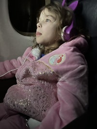 a girl in a pink jacket laying on a plane
